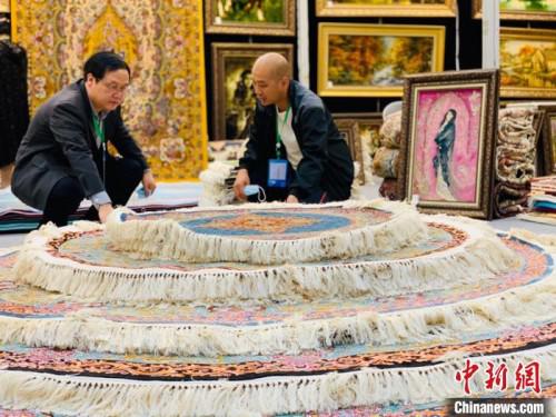 图为参展商向咨询的客商介绍地毯。 孙睿 摄